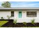 Charming home featuring a teal door and nicely landscaped front yard with dark mulch at 1886 San Mateo Dr, Dunedin, FL 34698