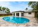A beautiful backyard with a pristine in-ground pool, travertine decking, and a well-maintained surrounding landscape at 1886 San Mateo Dr, Dunedin, FL 34698