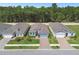 Aerial view showcasing three homes with well-maintained lawns, brick driveways, and lush green surroundings at 19629 Fort King Run, Brooksville, FL 34601