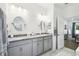 Well-lit bathroom with double sinks, modern fixtures, gray cabinets, and a marble-look floor at 19629 Fort King Run, Brooksville, FL 34601