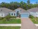 Charming one-story home featuring a well-manicured lawn, brick-paved driveway, and a blue exterior at 19629 Fort King Run, Brooksville, FL 34601