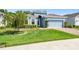 Charming blue home with a well-manicured lawn, landscaped garden beds, and a brick-paved driveway at 19629 Fort King Run, Brooksville, FL 34601