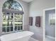Bright bathroom features a soaking tub under a large window with outdoor views at 2990 Eagle Estates W Cir, Clearwater, FL 33761