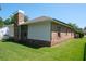 Back exterior view of a brick home with a large chimney, well-maintained lawn, and a sunny sky at 2990 Eagle Estates W Cir, Clearwater, FL 33761