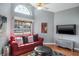Cozy living room featuring a red couch, ottoman and a large window at 2990 Eagle Estates W Cir, Clearwater, FL 33761