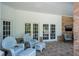Inviting covered patio with brick accents, white furniture, and double doors overlooking the backyard at 2990 Eagle Estates W Cir, Clearwater, FL 33761