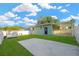 A fully fenced backyard features a concrete pad, lawn, storage shed, covered area and a purple door at 3002 E 24Th Ave, Tampa, FL 33605