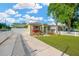 Charming single-story home featuring a lush lawn, American flag, and a long driveway with carport at 3002 E 24Th Ave, Tampa, FL 33605