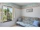 Well-lit bedroom featuring a futon, accent pillows, and a clear view of the trees outside the window at 3166 Lake Pine S Way # E3, Tarpon Springs, FL 34688