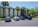 Low-rise condominium building exterior with parking spots, well-kept landscaping, and screen patios at 3166 Lake Pine S Way # E3, Tarpon Springs, FL 34688