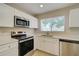Kitchen featuring stainless steel appliances, white cabinets, a window, and neutral countertops at 3262 Montclair Cir, North Port, FL 34287