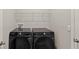 A laundry room featuring a black Samsung washer and dryer set with white wire shelving above for storage at 33581 Elm Hill Br, Wesley Chapel, FL 33545