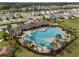 A beautiful community pool and clubhouse surrounded by palm trees and lush landscaping with neighborhood in the background at 33581 Elm Hill Br, Wesley Chapel, FL 33545