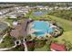 A beautiful community pool and clubhouse surrounded by palm trees and lush landscaping with neighborhood in the background at 33581 Elm Hill Br, Wesley Chapel, FL 33545