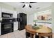 Eat-in kitchen featuring black appliances, white cabinets, and a breakfast nook with wood table at 37434 Derbyshire Dr, Zephyrhills, FL 33542