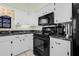 Updated kitchen with black appliances, white cabinets, and solid surface countertops at 37434 Derbyshire Dr, Zephyrhills, FL 33542