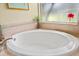 Close up of soaking tub in a bathroom featuring tile surround, a window, and a floral arrangement at 4111 70Th E Ave, Ellenton, FL 34222