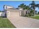 Charming home featuring a large garage, well-maintained lawn, and beautiful landscaping with palm trees at 4206 Morning Breeze Ct, Tampa, FL 33619