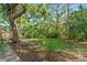 A tree-lined backyard with an expansive green lawn and landscaping at 4677 Del Sol Blvd, Sarasota, FL 34243