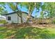 Exterior rear of home with backyard wooden deck surrounded by trees, foliage, and blue skies at 4677 Del Sol Blvd, Sarasota, FL 34243