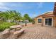 Landscaped backyard with a brick paver patio, complete with a dining table, leading to a tranquil pool area at 4815 Plantation Dr, Tampa, FL 33615
