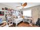 Cozy bedroom featuring a daybed, a ceiling fan, a built-in desk, and ample shelving for books and decorative items at 4815 Plantation Dr, Tampa, FL 33615
