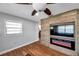 Bright living room with modern electric fireplace, wood-look floors, large window and contemporary ceiling fan at 4815 Plantation Dr, Tampa, FL 33615