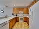 A well-lit kitchen featuring wood floors, white appliances and laminate countertops with wood cabinets at 5033 Blue Runner Ct, New Port Richey, FL 34652