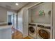 Laundry room with modern front-load washer and dryer and shelving, located off the hallway with wood floors at 5033 Blue Runner Ct, New Port Richey, FL 34652