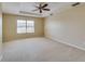 Spacious main bedroom with plush carpeting, a ceiling fan, and a bright window at 5033 Blue Runner Ct, New Port Richey, FL 34652