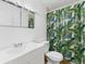 Bright bathroom with white sink and toilet, and colorful curtain with palm leaf pattern at 7535 Abonado Rd, Tampa, FL 33615