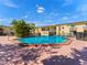 Community pool surrounded by palm trees and yellow buildings with balconies at 7535 Abonado Rd, Tampa, FL 33615