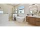 Bright bathroom featuring a standalone tub, glass-enclosed shower, and modern vanity with a white countertop at 7974 1St S Ave, St Petersburg, FL 33707