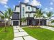 Modern two-story home with a beautifully landscaped yard, complemented by elegant palm trees and concrete driveway at 7974 1St S Ave, St Petersburg, FL 33707