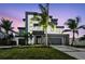 Modern two-story home boasts contemporary design, landscaping, and a multi-car garage at dusk at 7974 1St S Ave, St Petersburg, FL 33707