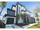 Stunning modern home featuring a black and white exterior, dual garages, and lush tropical landscaping at 7974 1St S Ave, St Petersburg, FL 33707