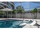 Inviting screened-in pool area featuring an umbrella, lounge chairs, and tropical landscaping, perfect for relaxation at 8515 Merrimoor Blvd, Seminole, FL 33777