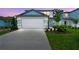 New construction home boasts a two-car garage, well-lit driveway, manicured lawn, and decorative bushes at 10520 Hidden Banks Gln, Parrish, FL 34219