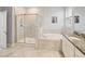 Bright bathroom featuring a glass-enclosed shower and a soaking tub with a granite-topped vanity at 10628 Bahama Woodstar Ct, Riverview, FL 33579