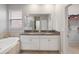 Bright bathroom featuring double sinks, granite countertops, a soaking tub, and a glass-enclosed shower at 10628 Bahama Woodstar Ct, Riverview, FL 33579