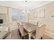 Elegant dining room with a large wooden table, upholstered chairs, modern chandelier, and bright windows at 10628 Bahama Woodstar Ct, Riverview, FL 33579