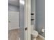Neutral toned bathroom with wood floors, a toilet with two shelves nearby, and a closed door to the hallway at 11136 Hartford Fern Dr, Riverview, FL 33569