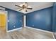 This bedroom has a ceiling fan, wood floors, a blue accent wall, and white trim at 11136 Hartford Fern Dr, Riverview, FL 33569