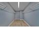 Walk-in closet with installed white rack shelving, neutral gray walls, and wood look flooring at 11136 Hartford Fern Dr, Riverview, FL 33569