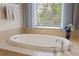 Close-up of large white soaking tub with tile surround and modern chrome faucet fixtures at 11607 Meridian Point Dr, Tampa, FL 33626