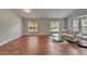 Bright living room with wood flooring, a cozy sofa, and glass tables, perfect for relaxing and entertaining at 11626 Pure Pebble Dr, Riverview, FL 33569