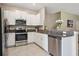 Well-lit kitchen with stainless steel appliances, granite counters, and white cabinets at 14323 Easy Goer St, Ruskin, FL 33573