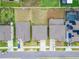 A top-down aerial view of a modern home's roof and lawn showing neighborhood street access and utility boxes at 16685 Parker River St, Wimauma, FL 33598