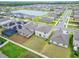 Aerial view of a modern home showing the backyard, green lawn, and proximity to a neighborhood pond at 16685 Parker River St, Wimauma, FL 33598