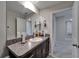 Bathroom featuring dark vanity, granite counter, sink, large mirror, and doorways at 16685 Parker River St, Wimauma, FL 33598